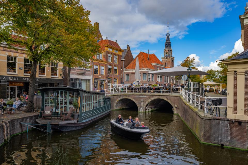 Bootje door de grachten van alkmaar met op de achtergrond een stenen brug